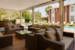 an outdoor patio with wicker furniture and a pool at Protea Hotel by Marriott Bloemfontein in Bloemfontein