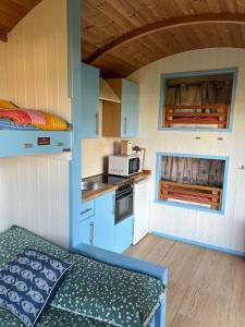 a small kitchen with a bed in a tiny house at Coral Shepherds Hut in Penally