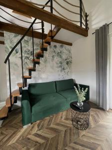 un sofá verde en una sala de estar con una escalera en Zajęcza Nora, en Polańczyk