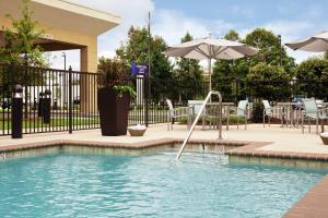a plunge pool with an umbrella and chairs at SpringHill Suites by Marriott Mobile West in Mobile