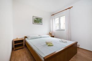 biała sypialnia z łóżkiem i oknem w obiekcie Nice Apartment Silvia w Novalji