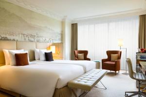 ルツェルンにあるルネッサンス ルツェルン ホテルの大きなベッドと椅子が備わるホテルルームです。