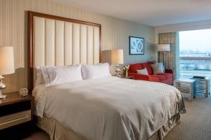 Cette chambre d'hôtel comprend un grand lit et un fauteuil rouge. dans l'établissement Renaissance Newark Airport Hotel, à Elizabeth