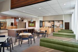 Fairfield Inn & Suites by Marriott Asheville Airport/Fletcher في فليتشر: مطعم ذو أثاث أخضر وطاولات وكراسي