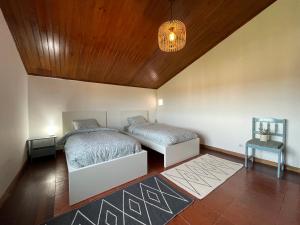 um quarto com 2 camas e um tecto de madeira em NO CEU - A fully private flat in the sky with Ocean view em Atouguia da Baleia
