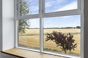an open window with a view of a field at Sigerslevhus Stevns Klint in Store Heddinge
