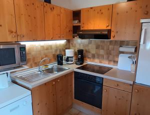 a kitchen with wooden cabinets and a sink and a microwave at Sonnenblick in Fischen