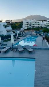 une grande piscine avec des chaises et un hôtel dans l'établissement Estepona South bay, à Estepona