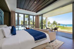 a bedroom with a large bed with a view of the ocean at Danang Ocean Resort & Spa Non Nuoc Beach Villas in Danang