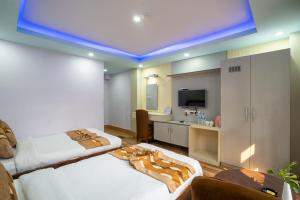 Cette chambre comprend 2 lits et une télévision. dans l'établissement Avocado Orchid Resort, à Heṭauḍā