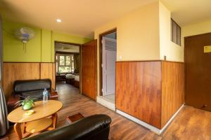 a living room with a table and a chair at Avocado Orchid Resort in Heṭauḍā