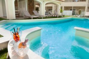 a swimming pool with a drink on a table next to it at Suimi's Hotel in Villasimius