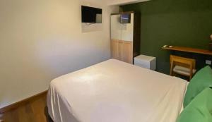 1 dormitorio con cama blanca y pared verde en The Lavana Villa Sutji Sanur, en Sanur