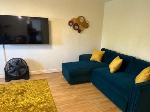 a living room with a blue couch and a tv at Modern Spacious Gated Two Bedrooms Apartment in Stifford