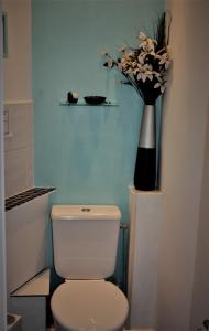 a bathroom with a toilet and a vase with flowers at Gite de Sarah 