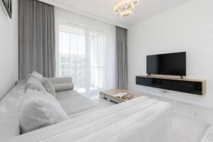 een witte woonkamer met een bank en een tv bij Praga Arte Apartments with Parking & Balcony by Renters in Warschau