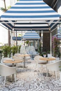 eine Terrasse mit Tischen und Stühlen sowie einem blauen und weißen Schirm in der Unterkunft Hotel Beaux Arts, Autograph Collection in Miami