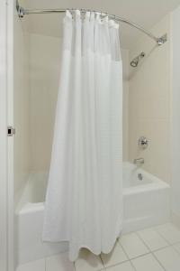 a bathroom with a white shower curtain next to a tub at Courtyard Atlanta Norcross/Peachtree Corners in Norcross