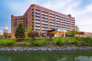 a large building with a river in front of it at Sheraton Lisle Naperville Hotel in Lisle