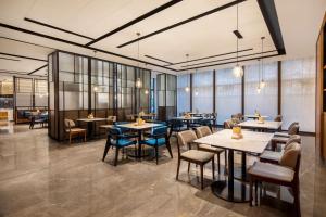 a restaurant with tables and chairs and windows at Fairfield by Marriott Hangzhou Xiaoshan in Hangzhou