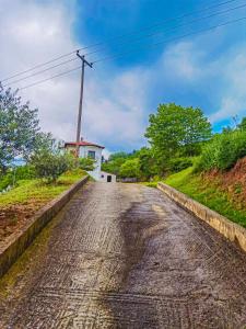 un camino vacío con un molino de viento a lo lejos en Villa Etheras - Nested between Nature by Amazing View - 5 mins from Edessa, en Édessa