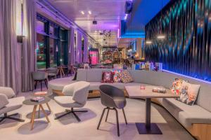 a restaurant with a couch and chairs and tables at Moxy Munich Messe in Aschheim