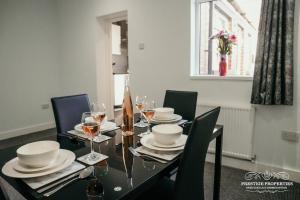 a dining room with a table with chairs and wine glasses at Dover St by Prestige Properties SA in Barrow in Furness