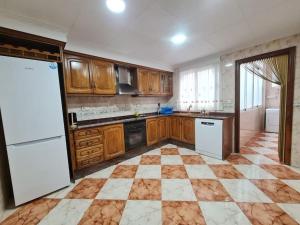 eine Küche mit Holzschränken und einem weißen Kühlschrank in der Unterkunft Apartamento en Santa Pola playa Levante in Santa Pola