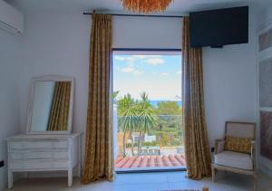 Zimmer mit einem Fenster mit einem Stuhl und einem Spiegel in der Unterkunft Villa La Residence Ibiza in San Jose de sa Talaia