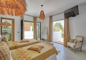 1 Schlafzimmer mit 2 Betten, einem Stuhl und einem TV in der Unterkunft Villa La Residence Ibiza in San Jose de sa Talaia + 49 Fotos