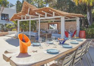 einen Holztisch mit Tellern und Gläsern auf einer Terrasse in der Unterkunft Villa La Residence Ibiza in San Jose de sa Talaia