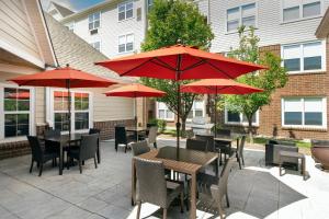 patio ze stołami i krzesłami z czerwonymi parasolami w obiekcie Residence Inn Denver South/Park Meadows Mall w mieście Centennial