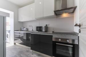una cocina con electrodomésticos negros y armarios blancos en Vita Portucale ! Almada Balcony, en Almada