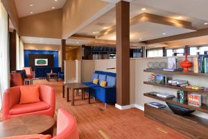 a living room with a red chair and a blue couch at Courtyard by Marriott Dallas Northwest in Dallas