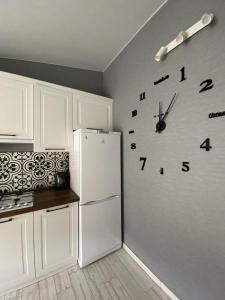 a kitchen with a refrigerator and a clock on the wall at GIL Apartments, Volodimirskaja 90.212 - Majetok Bozdosh in Uzhhorod