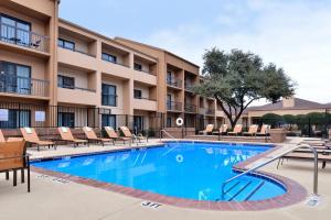 a swimming pool in front of a hotel with lounge chairs at Courtyard by Marriott Dallas Northwest in Dallas