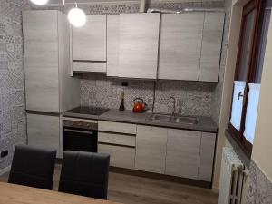 - une cuisine avec des placards blancs, un évier et une table dans l'établissement CASA VACANZE FRANCIACORTA, à Colombaro