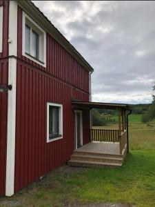 un granero rojo con porche y terraza en Vackert naturnära i Höga Kusten 