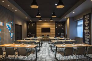 una sala da pranzo con tavoli, sedie e schermo di MOXY Tokyo Kinshicho a Tokyo