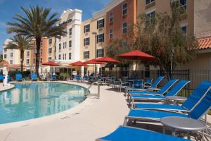 a swimming pool with blue lounge chairs and umbrellas at TownePlace Suites The Villages in The Villages