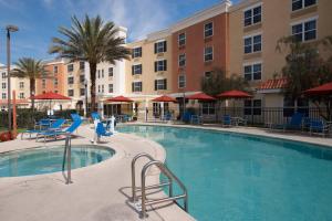 a swimming pool at a hotel with chairs and buildings at TownePlace Suites The Villages in The Villages