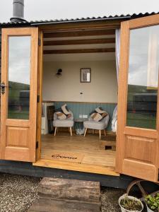 an open door of a house with two chairs and a porch at Silver Fern Glamping in Aberystwyth