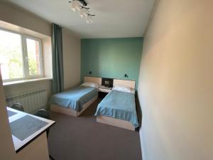 a room with two beds and a desk and a window at Ulpan Mini Hotel in Astana