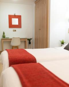 a bedroom with two white beds and a red blanket at Oasis Playa Maspalomas in Maspalomas