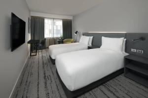 a hotel room with two beds and a television at Courtyard by Marriott Brisbane South Bank in Brisbane