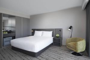 a bedroom with a white bed and a chair at Courtyard by Marriott Brisbane South Bank in Brisbane