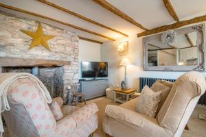 a living room with a couch and a stone fireplace at Cottage on the Dart- Riverside Fishermans Cottage in Stoke Gabriel