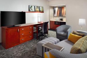 a hotel room with a desk with a tv and a couch at Courtyard by Marriott Greensboro in Greensboro