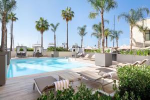 a swimming pool with chaise lounge chairs and palm trees at Riviera Marriott Hotel La Porte De Monaco in Cap d'Ail