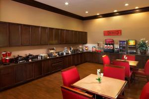 a restaurant with tables and red chairs and a kitchen at TownePlace Suites Houston Intercontinental Airport in Houston